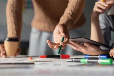 UX UI stratejileri hakkında bir tartışmaya katılan bir ekip, ortak çalışma ortamında çizimler, işaretler ve dijital araçlar kullanır.