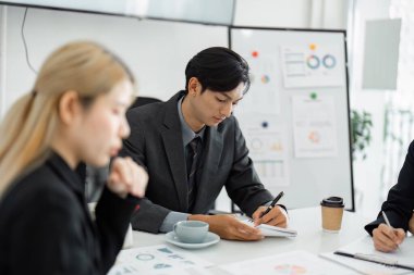 Bir iş adamı, çağdaş ofis ortamında mali belgeleri incelerken not almaya odaklanır..