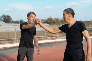 İki son sınıf öğrencisi antrenmandan sonra yumruk tokuşturuyor, yoldaşlık, fitness ve sonraki yıllarda birlikte aktif kalmanın zevkini vurguluyorlar..