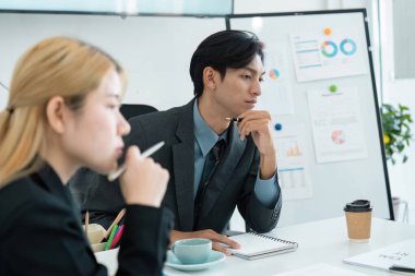 Stratejik bir toplantı sırasında mali raporları analiz eden iki özenli iş adamı, çağdaş bir çalışma alanında eleştirel düşünce ve işbirliğini vurguladı.