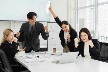 Bir grup profesyonel, iş toplantısında başarılarını sevinçle kutluyor, takım çalışması ve pozitif çalışma kültürü sergiliyor.