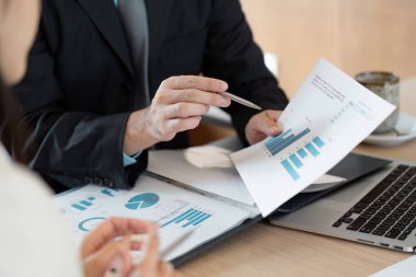 Yöneticiler mali raporları gözden geçirir ve veri içgörülerini tartışırlar, profesyonel bir ortamda işbirliği ve stratejik planlamayı vurgularlar.