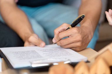 Finansal belgeler üzerinde birlikte çalışan evli bir LGBTQ çifti, takım çalışmalarını ve konforlu bir ev ortamında ortak finansal hedeflere olan bağlılıklarını vurguluyor.