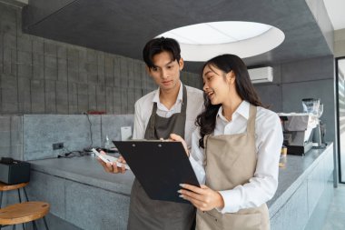 Bir barista ve kafe müdürü, şık bir kafe ortamında etkili bir takım çalışması ve iletişim sergileyerek, birlikte planları ve güncellemeleri araştırır..