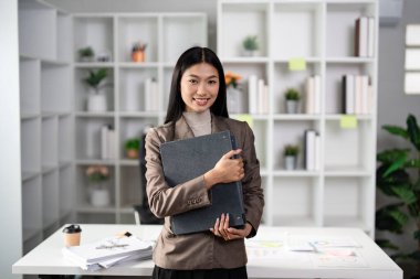 Kendine güvenen genç bir iş kadını modern ofis ortamında profesyonelliği ve başarıyı sembolize eden bir portföye sahip..