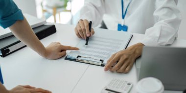 Profesyonellerin elleri bir toplantı sırasında belgelere işaret ediyor, işbirliği ve ayrıntılı tartışma.