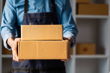 Bir işletme sahibi paketleri teslimat için hazır tutar, çevrimiçi bir işletmede müşteri hizmetlerine olan bağlılığı ve verimli işlemleri vurgular.