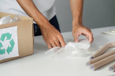 Bir kişi, sürdürülebilir uygulamalara ve çevresel bakıma olan bağlılığını gösteren, düzenli bir çalışma alanında plastik atık ve geri dönüşüm materyalleri sınıflandırıyor.