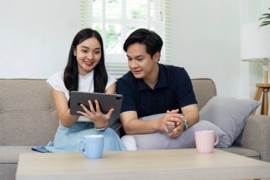 Bir çift, sıcak bir ev ortamında, bağlantılarını ve zevklerini gösteren bir tablet kullanırken keyifli bir anı paylaşıyor..