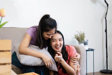 Neşeli bir çift, yumuşak yastıklar ve çiçeklerle çevrili kanepede neşeli bir etkileşimden zevk alır. Sevgi ve bağlarını gösterirler..