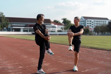 İki son sınıf öğrencisi bir pistte ısınma egzersizleri yaparken sağlıklarını ve zindeliklerini arttırıyorlar..