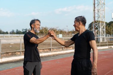 İki son sınıf öğrencisi bir pistte el sıkışırken, sağlık ve arkadaşlığın önemini vurgularlar..