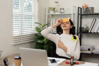 Bir kadın muhasebeci vergi belgelerini tutarken, mali yönetimin zorluklarını vurgularken hayal kırıklığı yaşıyor.