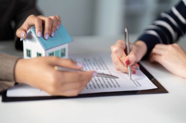 Bir emlakçı ve müvekkil, profesyonellik ve güveni vurgulayan bir emlak sözleşmesi imzalamak için işbirliği yaparlar.