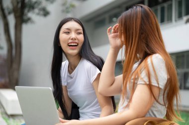 Üniversite hayatındaki işbirliğinin önemini vurgulayan iki öğrenci arasında neşeli bir etkileşim.