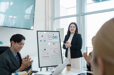 Çeşitli iş dünyasından profesyoneller, çağdaş bir çalışma alanında takım çalışması ve finans anlayışını vurgulayan bir meslektaşlarını alkışlıyor.