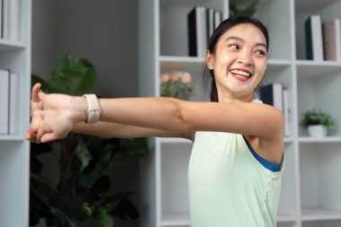 Neşeli bir kadın kollarını uzatıyor, ev ortamında vücut bulmuş zindelik ve sağlık..