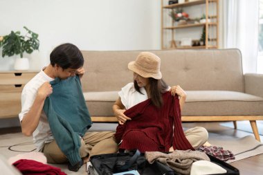 Yaşlı bir çift, seyahat maceralarına hazırlanırken bavullarından süveter seçiyor..