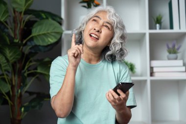 Son sınıf öğrencisi bir kadın telefonunu tutarken gülümsüyor. Barışçıl bir evde teknolojiyle nişanını sergiliyor..