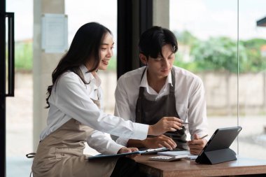 Canlı bir kafe ortamında, iki genç profesyonel girişimci girişimlerini, sergilenen takım çalışmalarını ve yeniliklerini geliştirmek için tabletleri üzerinde fikir alışverişinde bulunuyorlar..