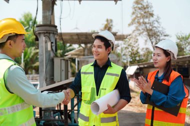 Bir ekip, sürdürülebilir uygulamaların önemini vurgulayarak, güneş enerjisi kurulumu planlarını tamamladıktan sonra kutlama yapıyor.