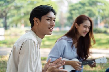 İki arkadaş keyifli bir anda ukulele oynayıp güzel bir açık hava ortamında atıştırmalıkların tadını çıkarıyorlar..