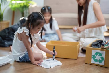 İki genç kız, geri dönüşümlü materyalleri annelerinin rehberliğinde araçları olarak kullanarak, yaratıcılıklarını sanatla ifade ediyorlar..