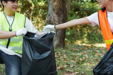 İki gönüllü, bir temizlik projesi sırasında birbirlerine plastik atık dağıtarak, toplumlarını temiz ve sürdürülebilir tutmaya odaklanan takım çalışmalarını sergilediler..