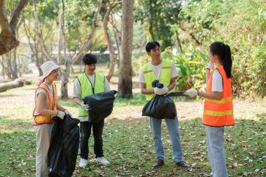 Çöp toplamak, park ortamında sürdürülebilirlik ve çevre sorumluluğunu desteklemek için birlikte çalışan dört farklı bireyden oluşan bir grup..