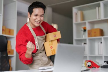 Genç bir girişimci başarılı bir çevrimiçi satışı sevinçle kutluyor ve e-ticaret işinin ödüllü anlarını sergiliyor..