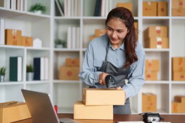 Modern bir çalışma alanında, genç bir girişimci çevrimiçi siparişleri için paketleri etkili bir şekilde tarar ve sorunsuz bir e-ticaret operasyonu sağlar..