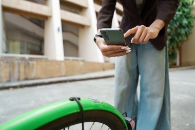 Bir profesyonel bisikletini mobil verimlilikle dengeler ve şehir yaşamında teknolojinin entegrasyonunu gösterir..