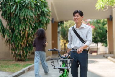 Genç bir profesyonel bisikletiyle yürürken esintili bir günün tadını çıkarır. Sürdürülebilir ulaşım ve sağlıklı yaşama olan bağlılığını yansıtır..