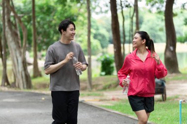 Dost canlısı bir ikili güzel bir parkta geziniyor, aktif bir yaşam tarzını benimserken neşe ve su anlarını paylaşıyor..