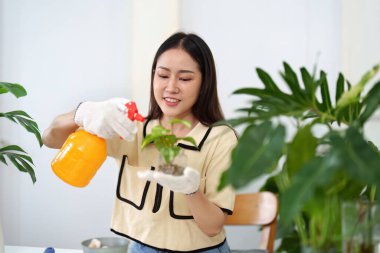 Kadın bitkilerini gülümseyerek suluyor, sürdürülebilir bahçıvanlık uygulamalarını savunurken doğayla bir bağ kuruyor..