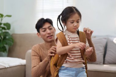 Kendini işine adamış bir baba, okul günü için kızlarını sırt çantasına yerleştirir. Okula dönüş deneyiminin verdiği heyecanı ve bağlılığı gösterir..