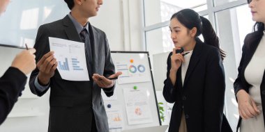 Meslektaşları profesyonel bir ortamda, takım performansını ve stratejisini geliştirmek için veri analizi ve fikir alışverişinde bulunuyorlar..