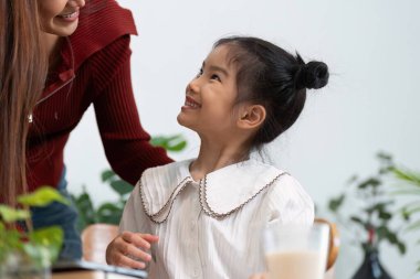 Anne-kız ikilisi sıcak bir gülümseme paylaşıyor, aile içinde paylaşılan mutluluk ve sevgiyi resmediyor okul günü için hazırlanırken..