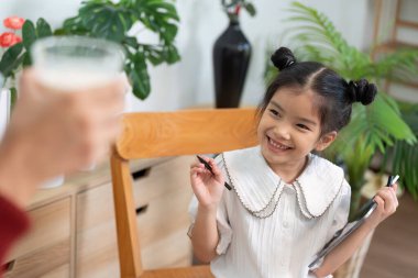 Hevesli bir kız, öğrenme sevincini vurgulayarak, çalışmalarıyla ilgili heyecanını dile getirirken annesiyle bir tebessüm paylaşıyor..