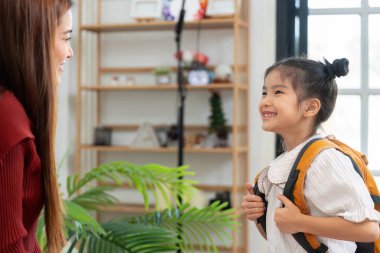 Kendine güvenen bir tavırla, kız sırt çantasıyla ayakta duruyor ve önümüzdeki güne heyecan saçıyor. Bu an eğitimde yeni başlangıçların neşesini özetliyor..