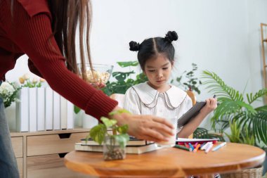 Şefkatli bir anne, kızı derslerine konsantre olup besleyici bir ortam yaratırken masaya bir şeyler koyar..