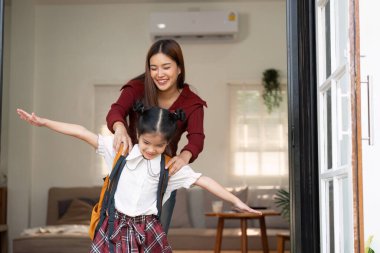 Bir anne kızına okula hazırlanırken neşe içinde yardım eder. Yeni bir öğrenme gününe başlamanın heyecanı ve neşesini yakalar..