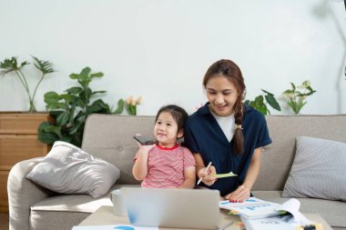 Bir anne ve kızı evde yaratıcı ve eğitici bir atmosfer yaratmak için dizüstü bilgisayarda çalışmaktan mutlu oluyorlar..