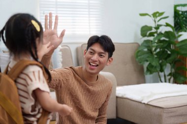 Neşeli bir anda, bir baba kızına beşlik çakar, okula hazır oluşunu kutlar. Görüntü pozitiflik ve cesaret veriyor..