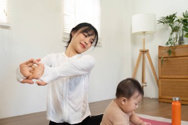 Kendini işine adamış bir anne evde esneme egzersizleri yapar. Yavru çocuğuyla bir anlık fitness ve bağlantının tadını çıkarır. Besleyici bir ortam yaratır..