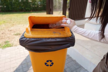 Kadın plastik şişeleri geri dönüştürürken yakalandı. Sürdürülebilir atık imha yöntemlerine bağlılığını yansıtıyor..