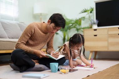 Her ikisi de sanatsal projelerine odaklanırken bir baba kızıyla ders çalışır ve birlikte öğrenmenin verdiği hazzı gösterir..