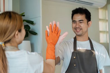 Modern bir ev ortamında temizlik, vitrin ve pozitiflik yaparken iki kişi beşlik çakıyor..