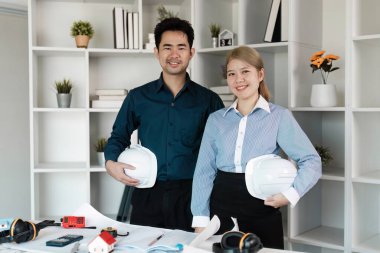 İki mimar modern ofis ortamında ev tasarımı planları, tasarım planları ve güvenlik donanımı sergilenmesinde işbirliği yaparlar..