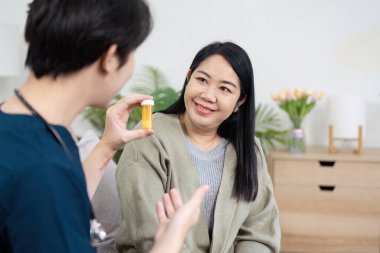 Bir sağlık uzmanı, güven ve anlayışı geliştirmek için konforlu bir evde bulunan bir hastayla ilaçları tartışır..